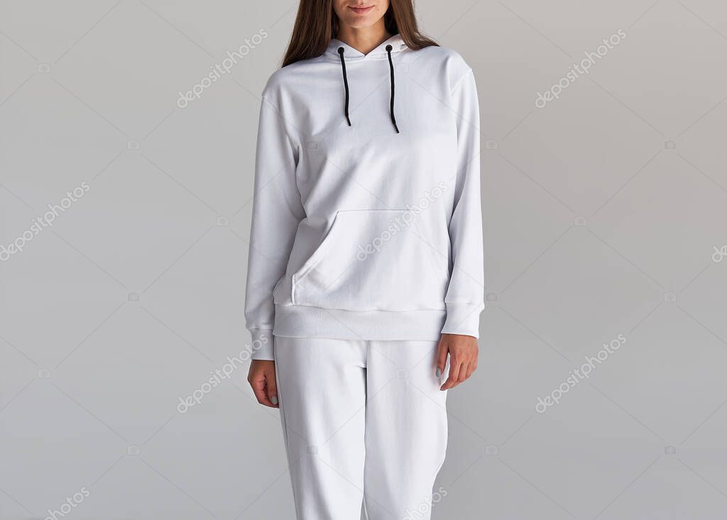 Woman wears white hoodie and white pants. indoor studio shot
