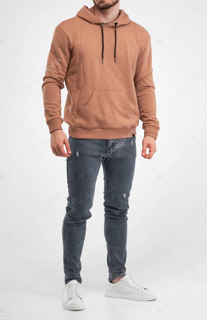 man wears beige hoodie. bearded young guy stands in khaki colored sweatshirt with hood. isolated catalogue shooting
