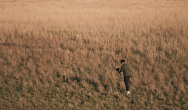 Film yapımcısı açık alanda kamerasını ve dengeleyicisini kullanarak video çekiyor. Koş-ve-silah film yap. Siyah giyen adam video çekiyor.