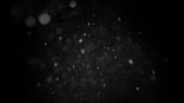 Luces Bokeh de nieve en cámara lenta sobre fondo negro, tiro de copos de nieve voladores en el aire — Vídeo de stock