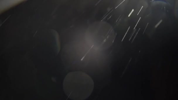 Optical flare with glowing dust. Snow falling with flare from the side on the black background — Stock Video