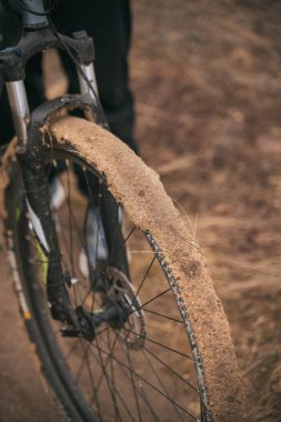 Çamurda kirli bisiklet tekerleği. Açık hava aktiviteleri sırasında çamurlu dağ bisikleti lastiği. Üzerinde kil olan ön tekerlek yakın plan.