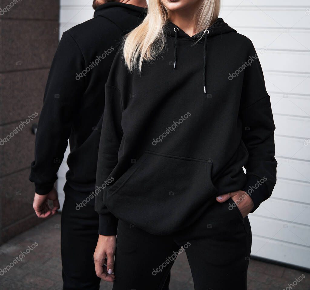 Woman and man wear black hoodie without a logo. No logo basic sportswear. Long sleeve sweatshirt mockup