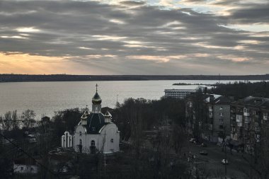 Nehirdeki doğu Ortodoks Kilisesi. Gökyüzü Tanrı ışınlarıyla hareket ediyor. Altın kubbeli kilisenin çöküşü. Kilisenin kubbesi gökyüzünü yansıtıyor.