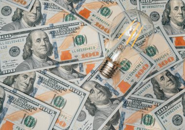 100 usd düz zemin üzerinde ampul. Elektrik faturaları için ekonomi kavramı. Daha az harcama için ışık tasarrufu fikri.
