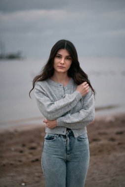 Yalnız kadın sahilde yürüyor. Akşamları deniz kenarında yürüyen esmer elbiseli bir kadın. Baharda deniz kenarında bir kız..