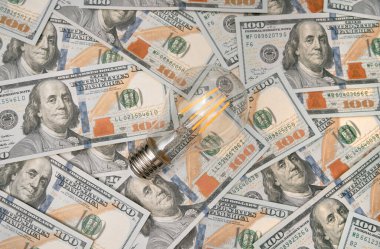 100 usd düz zemin üzerinde ampul. Elektrik faturaları için ekonomi kavramı. Daha az harcama için ışık tasarrufu fikri.