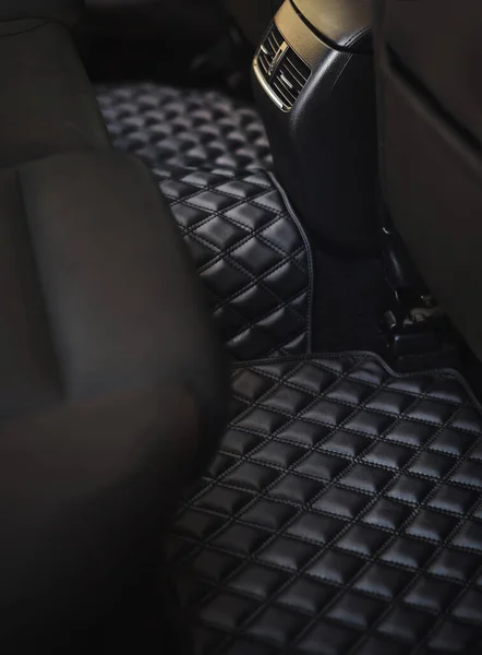 Car floor mat with diamond pattern. Ecoleather dark floormat on the second row in the modern vehicle. transmission tunnel on the passenger seat site in the vehicle. concept of luxury and clean car