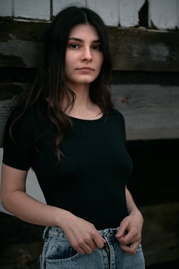 Kumsalda şehvetli ve muhteşem bir esmer. Sahilde sonbahar sezonu boyunca giyinik bir kadın. Siyah gömlek ve kot pantolon giyen kahverengi saçlı bir kızın portresi..