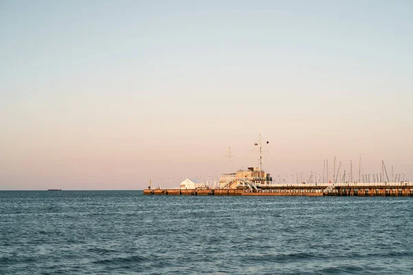 日没時に海の木製の桟橋 夏休み中の海辺でのリラクゼーションの概念 — ストック写真