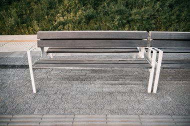 Tren peronundaki bankta beyaz boyalı demir ve gri ahşap. Şehir altyapısı kavramı.