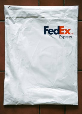 FedEx Express paketi. Karanlık masa arkaplanındaki FedEx nakliye çantasının yaşam tarzı resmi