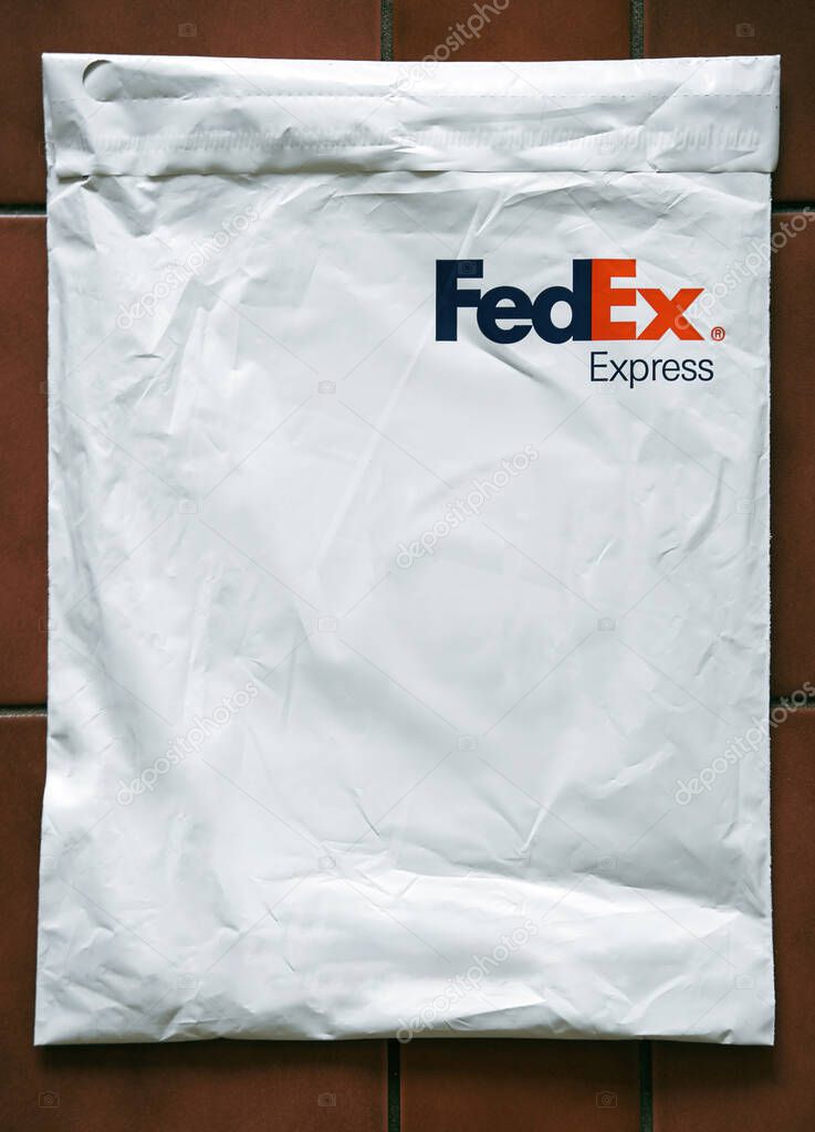 FedEx Express parcel. Lifestyle picture of the FedEx shipping bag on dark table background