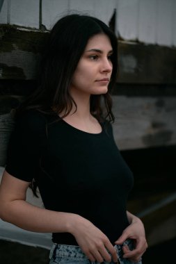 Kumsalda şehvetli ve muhteşem bir esmer. Sahilde sonbahar sezonu boyunca giyinik bir kadın. Siyah gömlek ve kot pantolon giyen kahverengi saçlı bir kızın portresi..