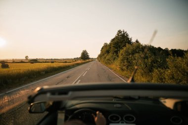 Gün batımında üstü açık araba yolda.