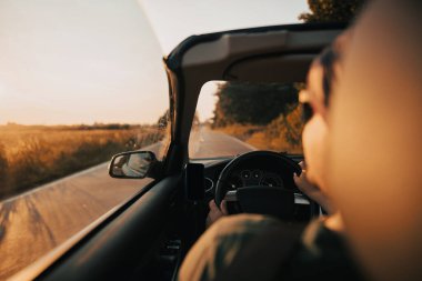 Yaz günbatımında üstü açık bir araba sürüyorum.