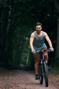 Ormanda bisiklet süren genç bir adam. Ormanda rekabetçi bisiklet yarışı. Dümeni olmayan erkek motorcu..