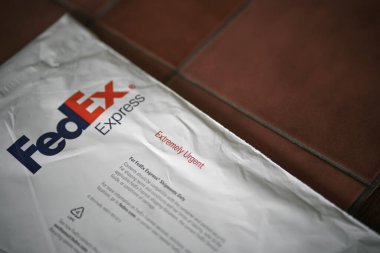 FedEx Express paketi. Karanlık masa arkaplanındaki FedEx nakliye çantasının yaşam tarzı resmi