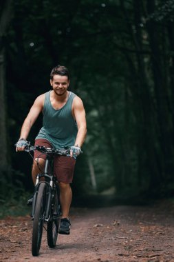 Ormanda bisiklet süren genç bir adam. Ormanda rekabetçi bisiklet yarışı. Dümeni olmayan erkek motorcu..