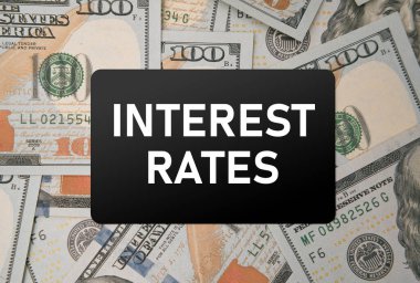 Yüz dolarlık banknotların üzerindeki kredi kartında Faiz Oranları yazıyor. Bankadan kredi alırken finans stratejisi ve iş planı kavramı