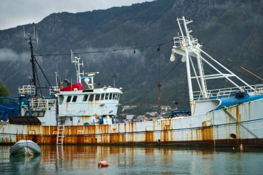 Durgun mavi suda süzülen paslı beyaz bir tekne.