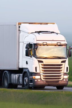 Beyaz nakliye kamyonu kırsal alandan geçiyor.