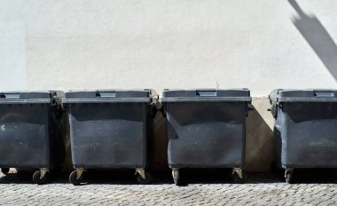 Outdoor dumpsters in front of city background