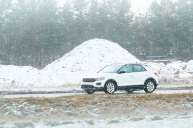 Kış boyunca karlı yol kenarında giden SUV.