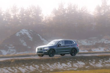 Boş arazinin yanından geçen lüks bir SUV.