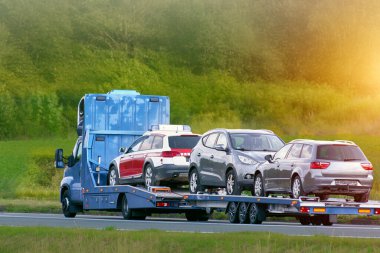 Beyaz araba sarı kurtarma kamyonuyla taşınıyor.