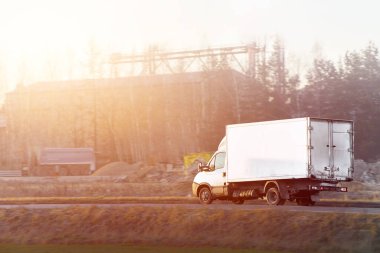 Manzaralı arka planı olan kargo aracı yolda.