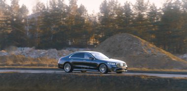 Siyah lüks sedan yolda gidiyor.