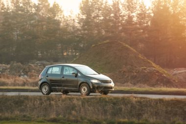Huzurlu kırsal yolda ilerleyen kompakt araba