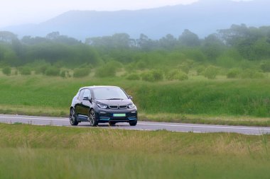 Sakin bir kırsal yolda elektrikli bir araç sürüyor.