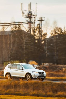 Yeşil ağaçların yanında araba sürüyor.