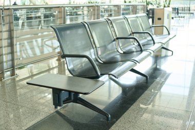 Boş havaalanı, güneş ışığı yansımalı sandalyeleri bekliyor.