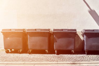 Sokak çöplükleri alçı duvarın önünde duruyor.