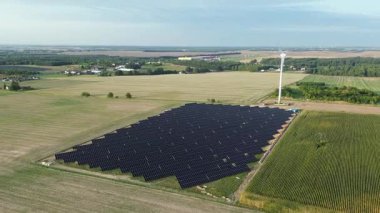 Fotovoltaik paneller ve mavi gökyüzünün altında rüzgar türbini