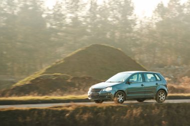 Kırsal yolda giden küçük bir hatchback arabası.
