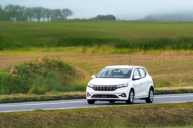 Manzaralı ülke yolunda küçük bir hatchback otomobili
