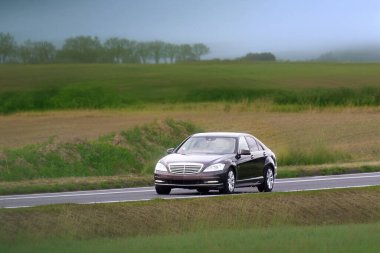 Manzaralı otoyolda giden özel sedan.