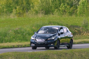 Sakin bir köy yolunda yeni elektrikli otomobil sürüyor