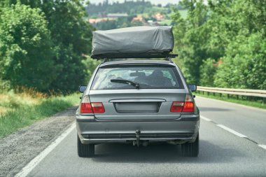 Çatı çadırı olan eski bir araba manzaralı yolda gidiyor.