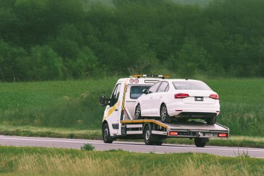 Flatbed kamyonu ağır hasarlı araç taşıyor.