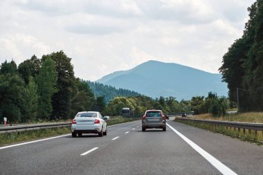 Dağ manzaralı araçlar yolda ilerliyor