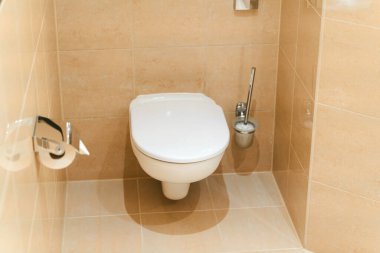 Zarif bir tuvalette, kapalı kapaklı, duvara asılmış bir tuvalet.