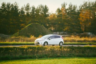 Beyaz modern hatchback yol kenarında sürüyor.