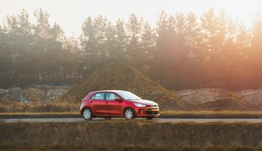 Kırsal yolda giden küçük bir hatchback arabası.