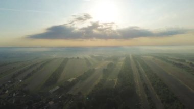 Tarımsal vadi ve tarlaların üzerinde gün doğumu sisi