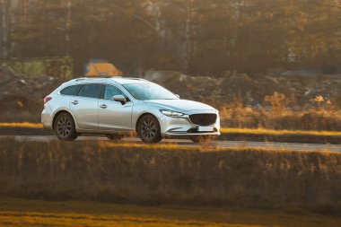 Beyaz araba kırsaldan geçiyor.